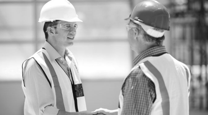 Two engineers shaking hands on a construction site